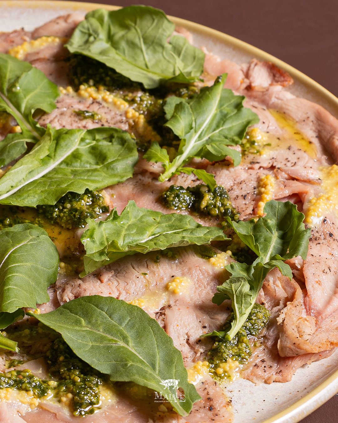 Carpaccio de Maiale, com rúcula e molho de mostarda.